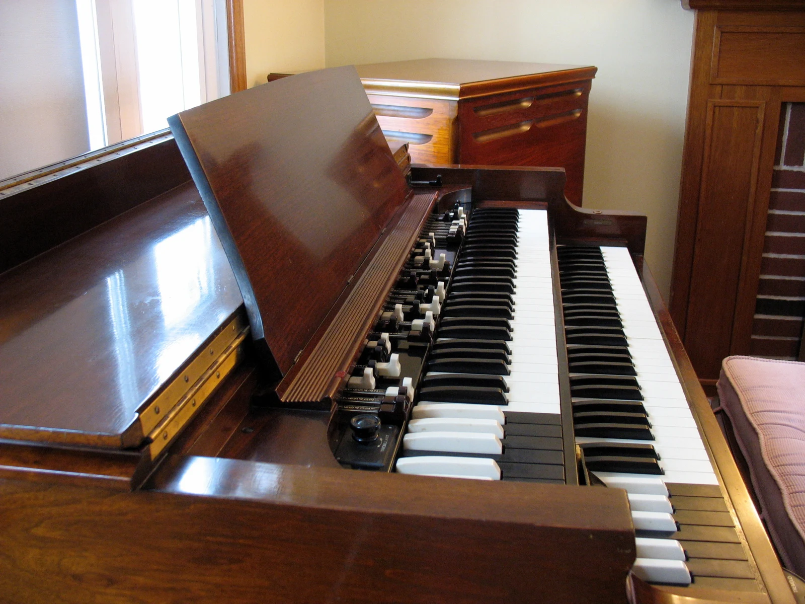 The dual keyboards of a wooden Hammond BC organ, with a Leslie cabinet behind it